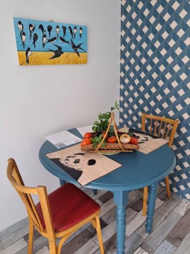 une table bleue avec un bol de fruits et un tableau dans l'établissement LES HIRONDELLES avec jacuzzi gratuit, à Soings-en-Sologne
