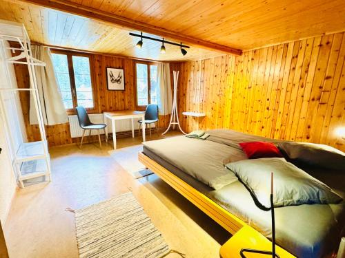 Cozy Apartment in Vintage House in Kandersteg في كانديرستيج: غرفة نوم بسرير كبير في غرفة بجدران خشبية