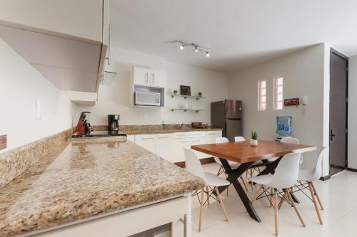 a kitchen with white cabinets and a wooden table at Via Tendenza Condos in Playa del Carmen