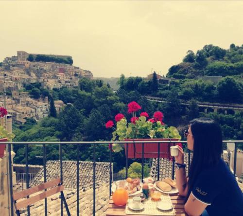 une femme assise à une table avec une tasse de café dans l'établissement B&B Cuore Barocco, à Raguse