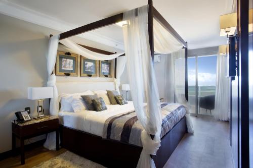 a bedroom with a canopy bed and a window at Royal Atlântica Macaé Hotel in Macaé