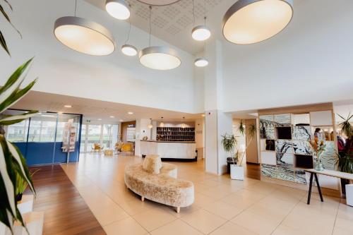 a large lobby with a chair and a table at Domitys Les Falaises Blanches in Bayeux