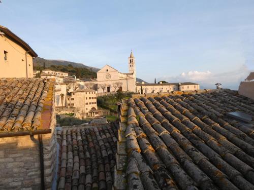 um grupo de telhados com uma igreja ao fundo em Scappo in Umbria, La casa di Eude em Assis