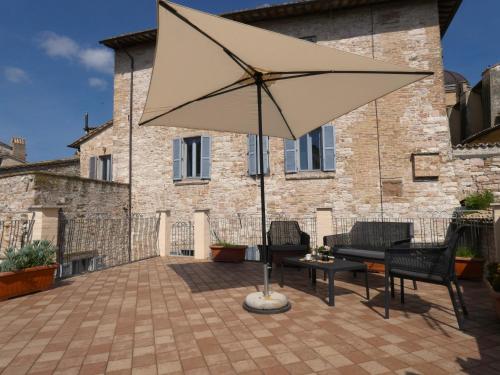 een patio met een tafel en een parasol bij Scappo in Umbria, La casa di Eude in Assisi