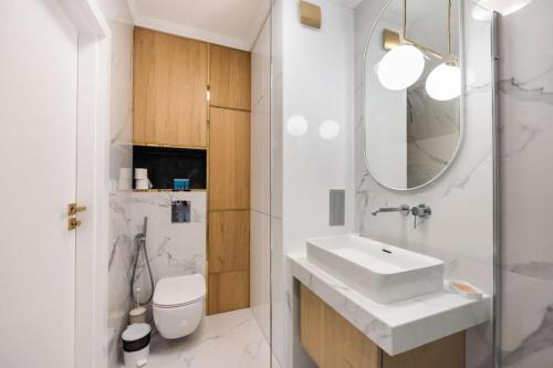 uma casa de banho branca com um lavatório e um espelho em Golden Apartment Prestige with Parking in Warsaw Bemowo em Warszawa