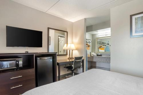 a hotel room with a bed and a desk with a television at Quality Inn Simpsonville-Greenville in Simpsonville