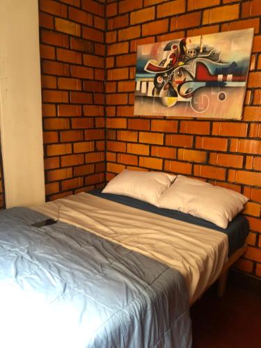 a bed in a brick room with a painting on the wall at Ginger Homes in Mizingo
