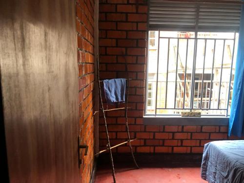 una habitación con una pared de ladrillo y una escalera junto a una ventana en Ginger Homes, en Mizingo