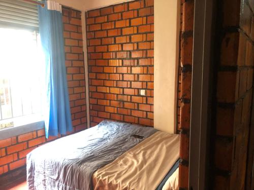 a bed in a room with a brick wall at Ginger Homes in Mizingo