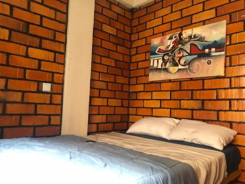 1 dormitorio con 1 cama y pared de ladrillo en Ginger Homes, en Mizingo