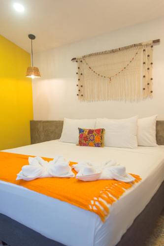 a bedroom with a bed with white sheets and an orange blanket at Hotel Boutique Casa Xaan in Valladolid