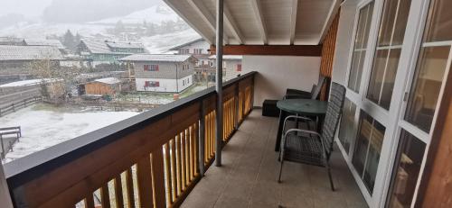 a balcony with a table and a view of a snow covered mountain at Landhaus Thaler in Mittelberg