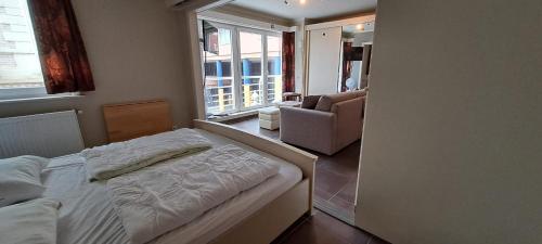 a bedroom with a bed and a living room at 1-slaapkamer appartement - vlak bij strand - parkeerplaats inclusief in Blankenberge