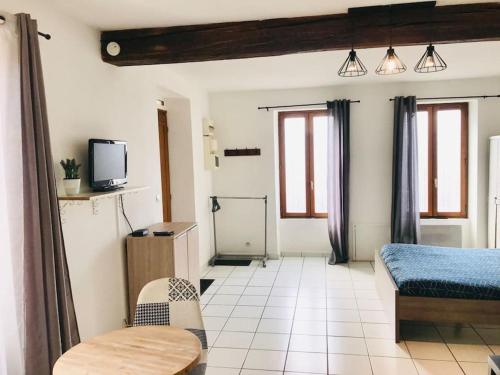 a bedroom with a bed and a table and a tv at Le Studio du 14 parking gratuit et arrivée autonome in Auxerre