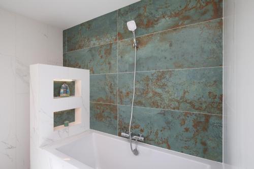a bathroom with a bath tub with a green wall at Vila Berg in Rovensko pod Troskami