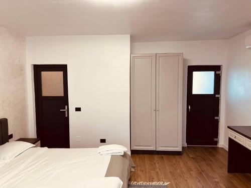 a bedroom with a white bed and two doors at Casa YDA in Horezu