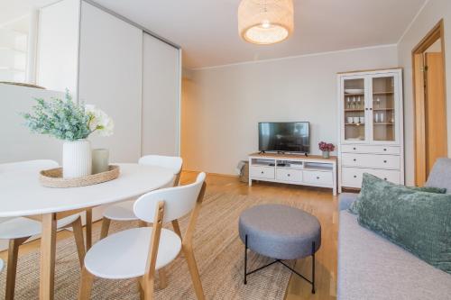 a living room with a table and chairs and a tv at Tiigi 8 Cozy Apartment in Tartu