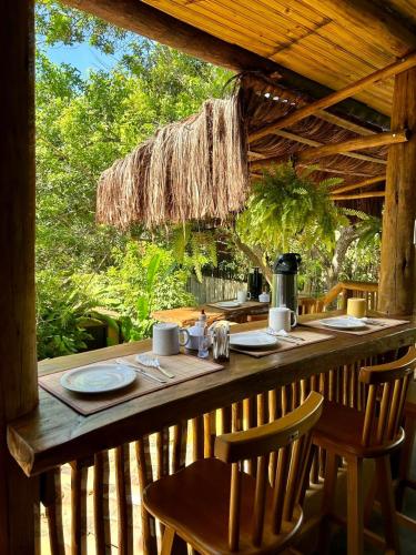 a wooden table with two chairs and a table with at Pousada Raiz Forte in Caraíva