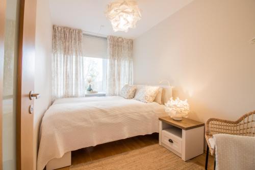 a white bedroom with a bed and a window at Tiigi 8 Cozy Apartment in Tartu