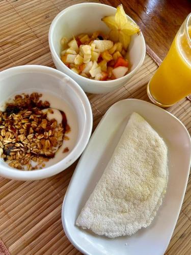 a table with three bowls of food and a bowl of sugar at Pousada Raiz Forte in Caraíva