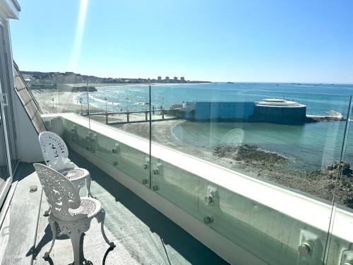 a balcony with two chairs and a view of the ocean at Eden Hotel - Beach Apartments & Suites in Saint Helier Jersey