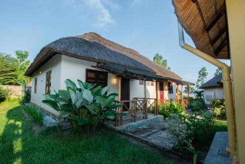 una pequeña casa blanca con techo de paja en Kazinga Wilderness Queen Elizabeth NP, en Katunguru