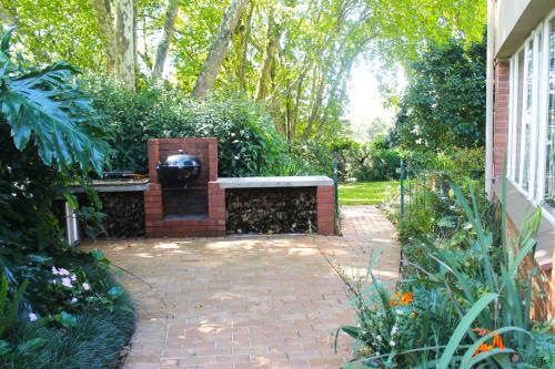 a brick patio with a grill in a garden at Umoya in Hilton