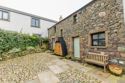 a stone house with a wooden door and a bench at HIGH TREES BYRE - Two bed Cottage with Log Burner & Incredible Views in Workington