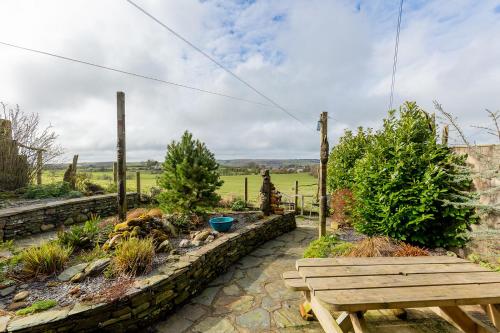 a wooden bench sitting in a garden with trees at HIGH TREES BYRE - Two bed Cottage with Log Burner & Incredible Views in Workington