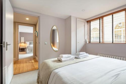 a white bedroom with a large bed and a mirror at Prime Covent Garden gem with Air-Con in London