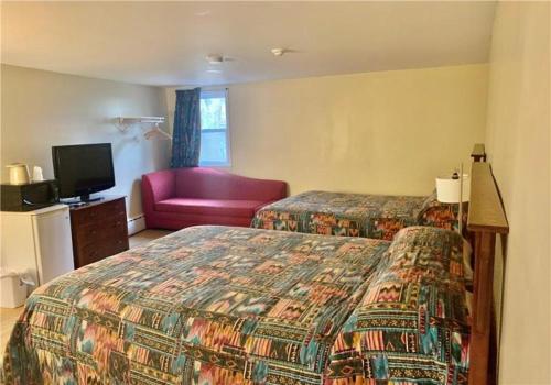 Habitación de hotel con 2 camas y sofá rojo en Stone-House Motel and Restaurant en Truro