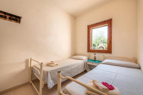 two beds in a room with a window at Ferienwohnung in San Teodoro mit Garten und Grill in San Teodoro