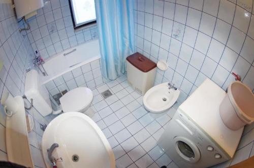 een witte badkamer met een toilet en een wastafel bij Wohnung in Pula mit Terrasse, Garten und Grill in Pula