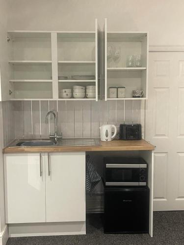 a kitchen with white cabinets and a sink and a microwave at Lovely Getaway Apartment in Wisbech in Wisbech