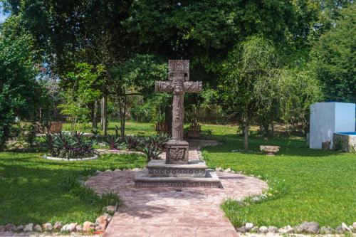 a stone cross in the middle of a garden at Hotel Boutique Casa Xaan in Valladolid