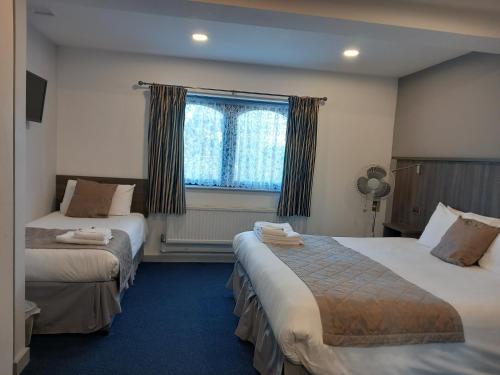 um quarto de hotel com duas camas e uma janela em Sandown Park Lodge em Esher