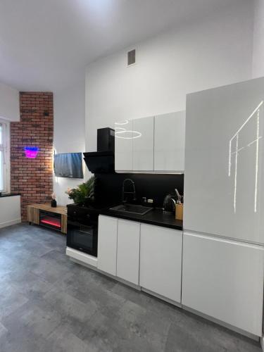 a kitchen with white cabinets and a black counter top at LOFT w centrum z jacuzzi in Wrocław