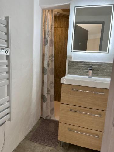 W łazience znajduje się umywalka i lustro. w obiekcie Maison de village w mieście Lédenon