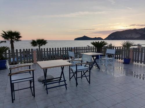 un patio con mesas y sillas con vistas al agua en Marilena's Beach House en Agios Georgios Pagon