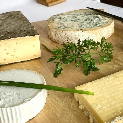 a bunch of cheeses on a wooden cutting board at Hôtel Restaurant Le Grillon in Chambon-sur-Lac