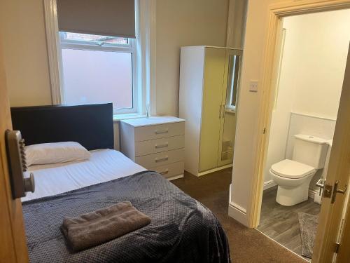 a bedroom with a bed and a toilet and a window at Rose House in Derby