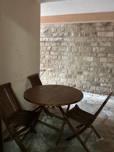 a wooden table and chairs in a room with a brick wall at Apartman Marko in Risan