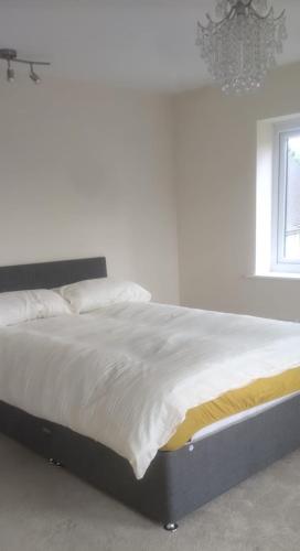 Una cama con sábanas blancas y una lámpara de araña en un dormitorio en Telford Guest House 1 en Telford