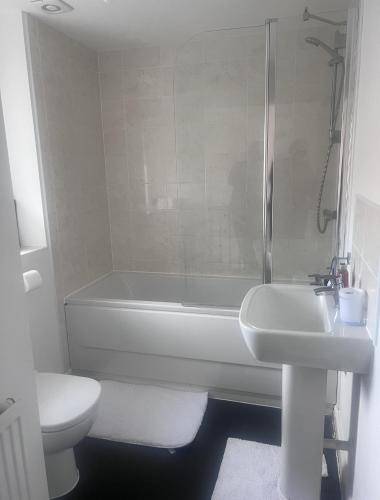 uma casa de banho com uma banheira, um lavatório e um WC. em Telford Guest House 1 em Telford