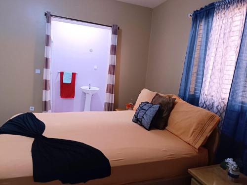 a bedroom with a bed with blue curtains and a sink at Pensão Dona Fica in Tarrafal