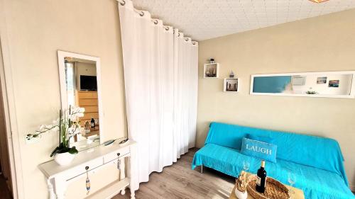 - un salon avec un canapé bleu et un miroir dans l'établissement Vaux sur Mer - EMPLACEMENT de CHOIX - APPARTEMENT - PLAGE de NAUZAN, à Vaux-sur-Mer