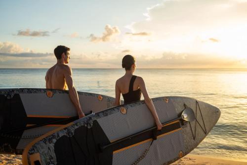 two men sitting in a surfboard on the beach at The Ritz-Carlton, Grand Cayman in George Town