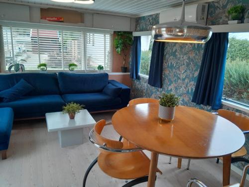a living room with a table and a blue couch at Stacaravan 426 met airco vakantiepark de Tien Heugten Schoonloo Drenthe in Schoonloo
