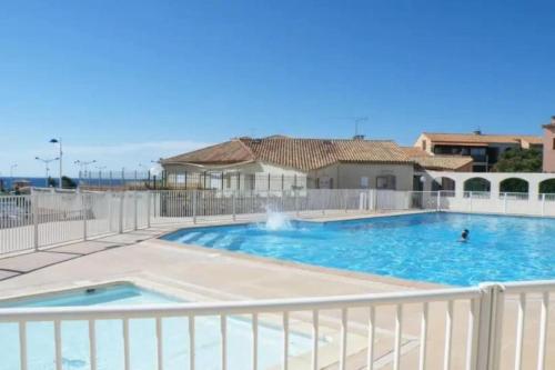 une grande piscine entourée d'une clôture blanche. dans l'établissement Studio lumineux, avec vue mer - Conciergerie Regnier -, à Sausset-les-Pins
