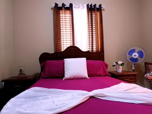 a bed with pink and white sheets and a window at Pensão Dona Fica in Tarrafal